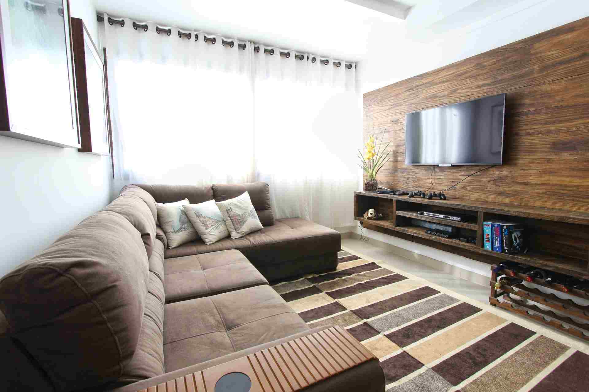 Contemporary living room featuring a brown sectional sofa, striped rug, and wooden TV console.