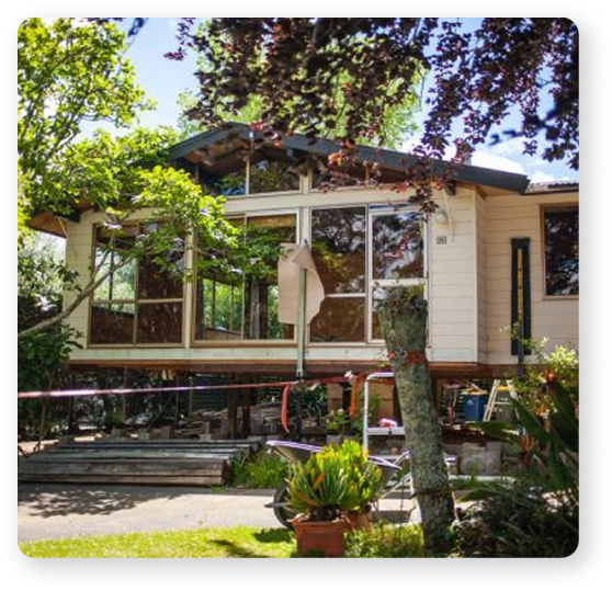 House lifted onto jacks and prepared for relocation in a leafy garden